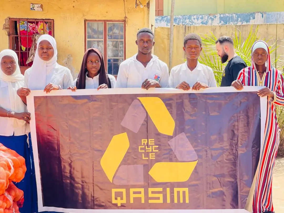 Elever på døveskolen i Gambia holder QASIM-banneret
